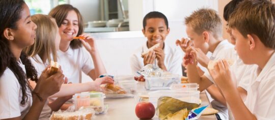 Enfants qui mangent un gouté ensemble autour de la table en souriant
