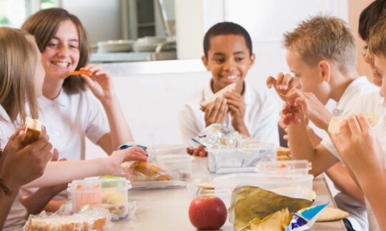 Enfants qui mangent un gouté ensemble autour de la table en souriant